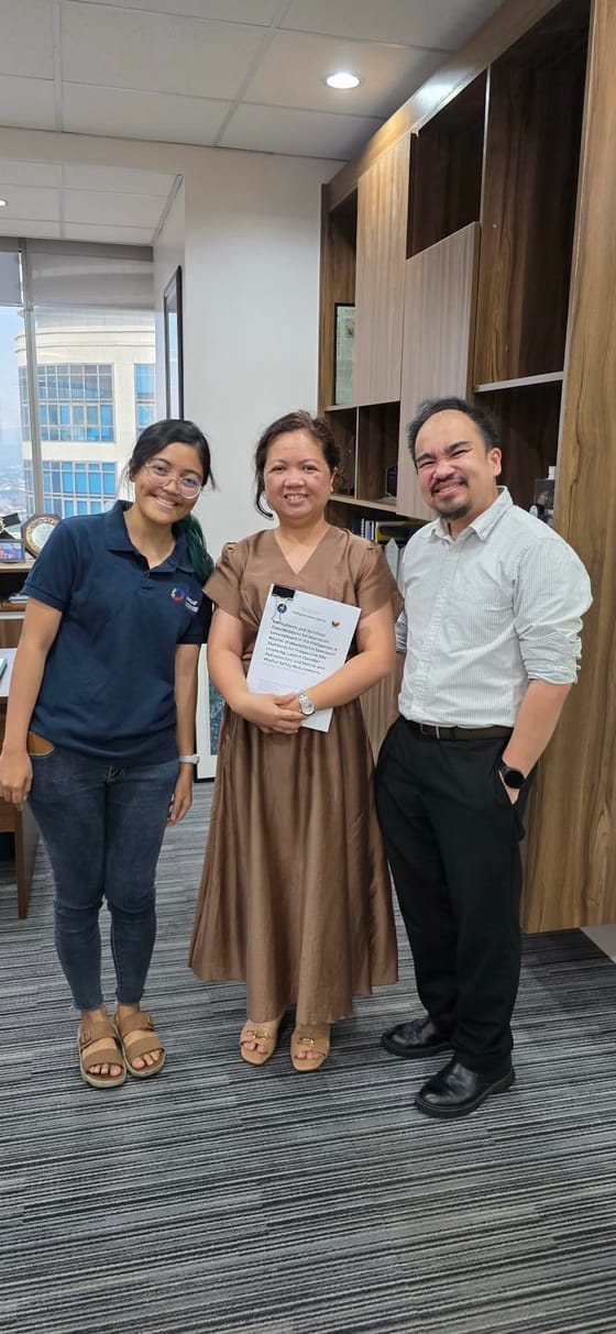 Rheanne standing with two colleagues in an office, holding a printed copy of the handbook.