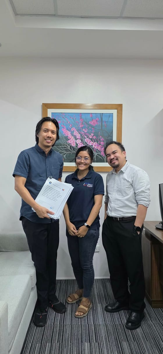 Rheanne with two colleagues in an office, presenting the handbook to camera.